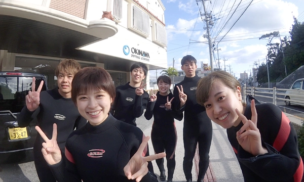 沖縄ダイビングセンターの店舗前で若い男女が集合写真
